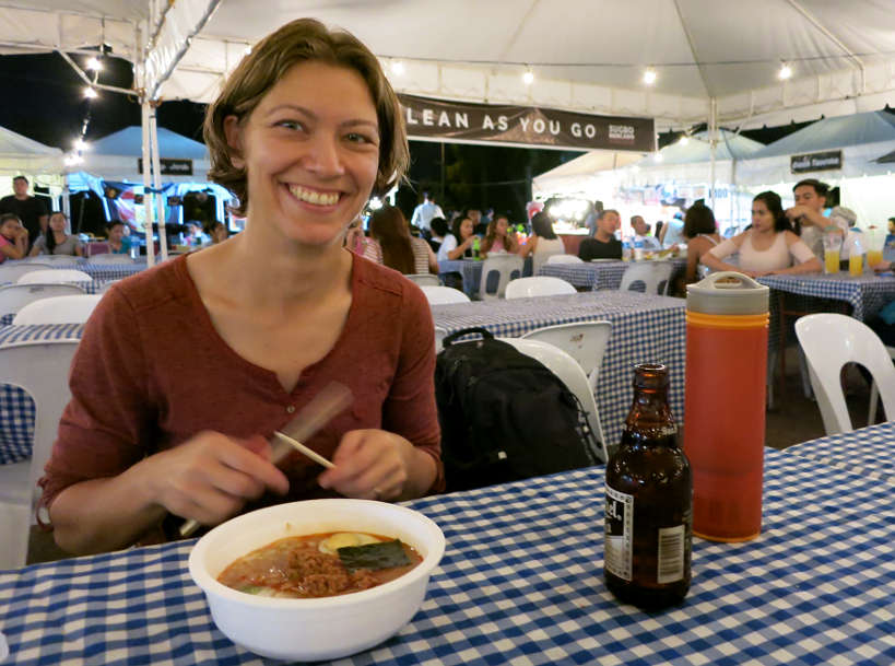 Claire at a street fair in the Philippines drinking water from a Grayl bottle in Southeast Asia Authentic Food Quest