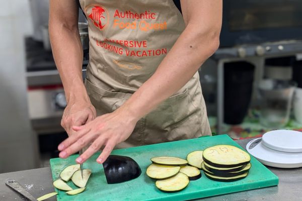 Guest preparing traditional parmigiana on an Authentic Food Quest cooking vacation